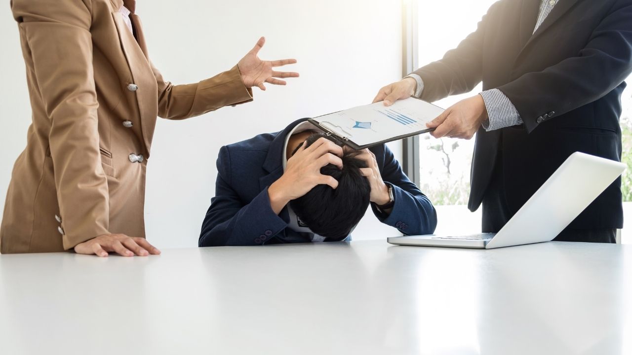 man with head down and two people standing near